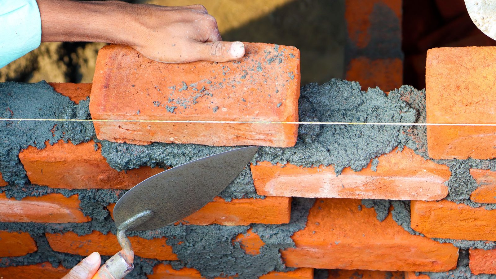 Bricklayer spreading mortar and laying a brick.