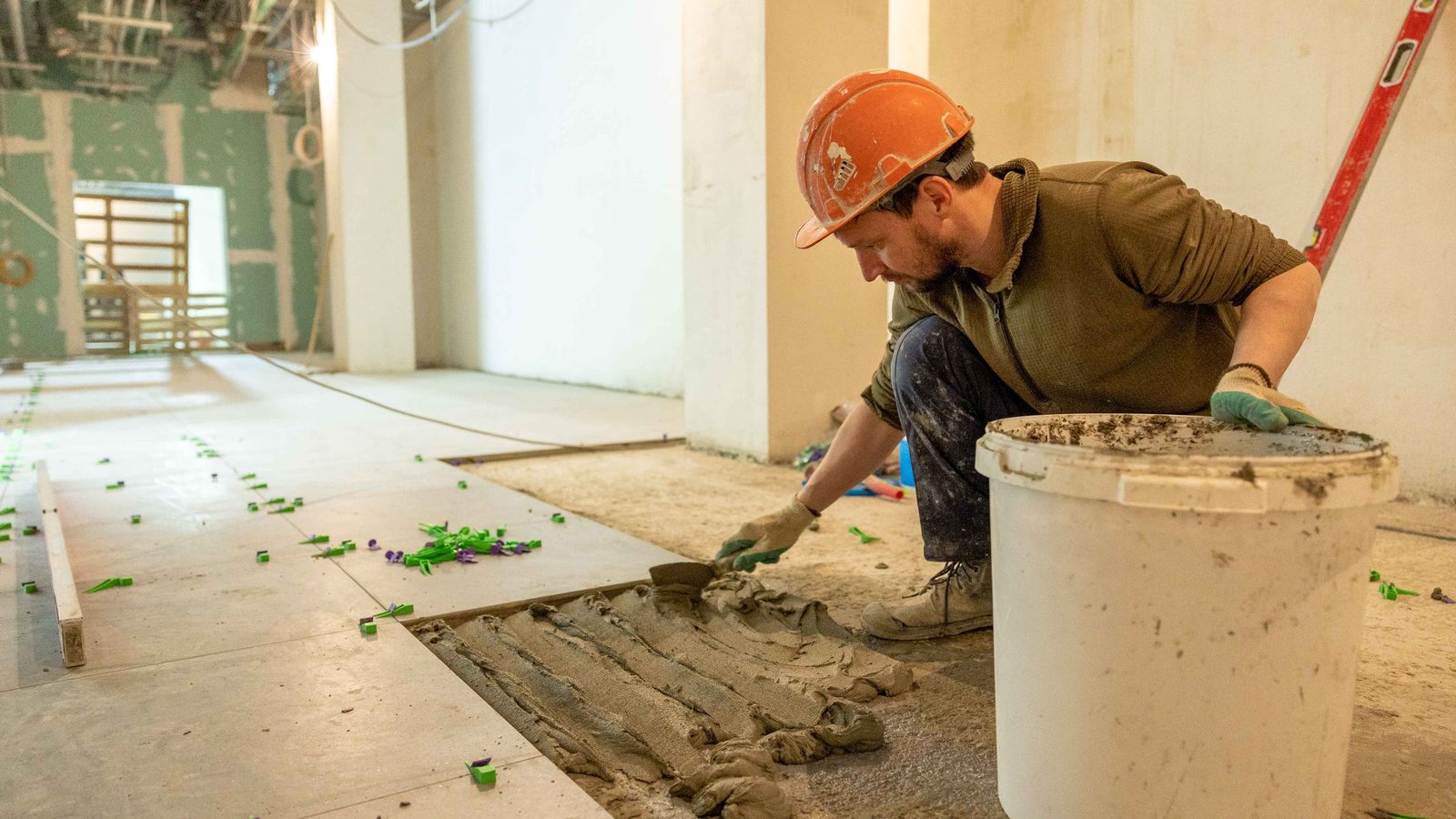 Worker levelling mortar in preparation for a new floor.