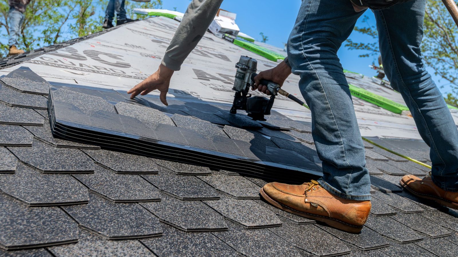 Roofer fastening shingles on a roof.